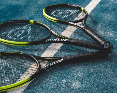 3 raquettes dunlop posées sur un court de tennis