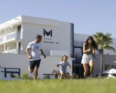 famille court dans l'herbe devant hotel avec piscine mouratoglou